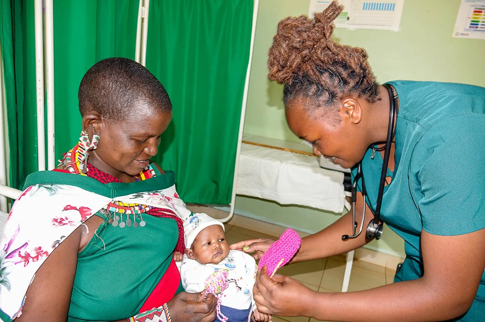 Sjuksköterska undersöker ett spädbarn som hålls av sin mamma på New Life Missions hälsoklinik