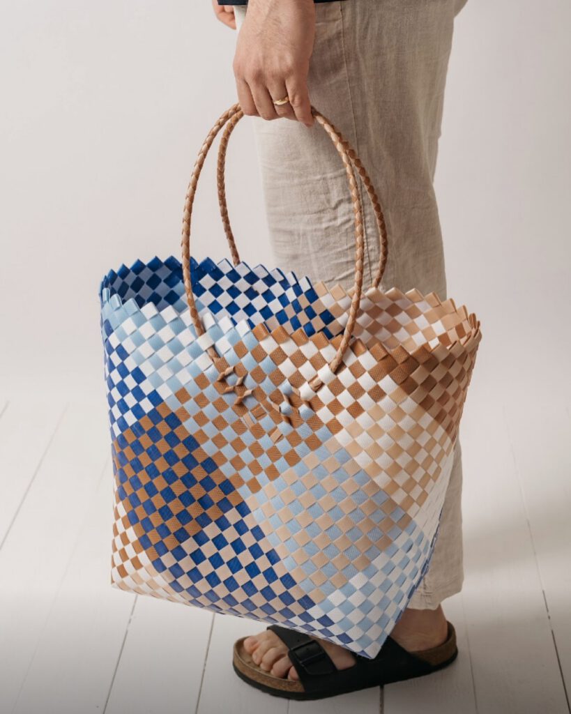 Kvinna som visar upp en färdig handflätad Lifebag-väska